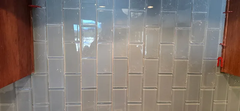 Glass subway tile backsplash grouted to a crisp finished line